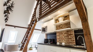 A modern kitchen with a brick wall, wooden beams, and a loft-style dining area. - Adelhoff (Osnabrueck)