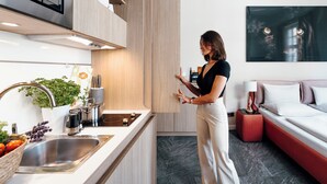 A modern kitchen with a built-in oven, a sink, and a countertop with a plant and a basket of fruit. - Adelhoff (Osnabrueck)