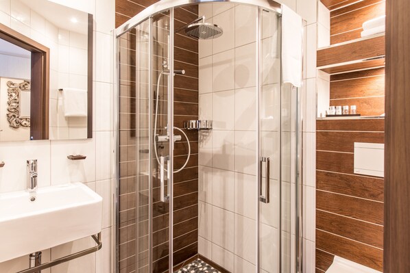 A modern bathroom with a glass-enclosed shower, a sink, and wooden paneling.