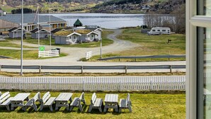 A view of a lakeside area with a row of picnic tables and a row of cabins. - Ulvik Camping (Ulvik)