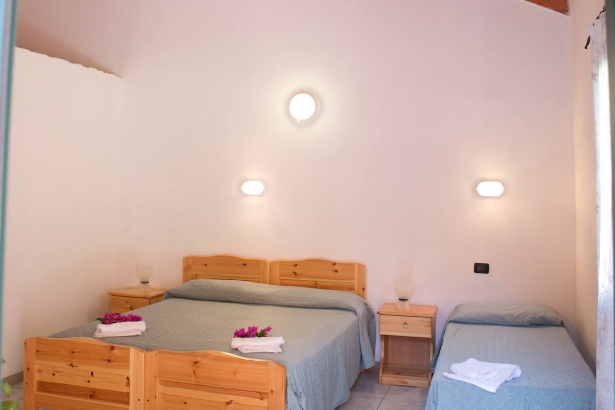 A bedroom with two wooden beds, a small bedside table, and a nightstand.