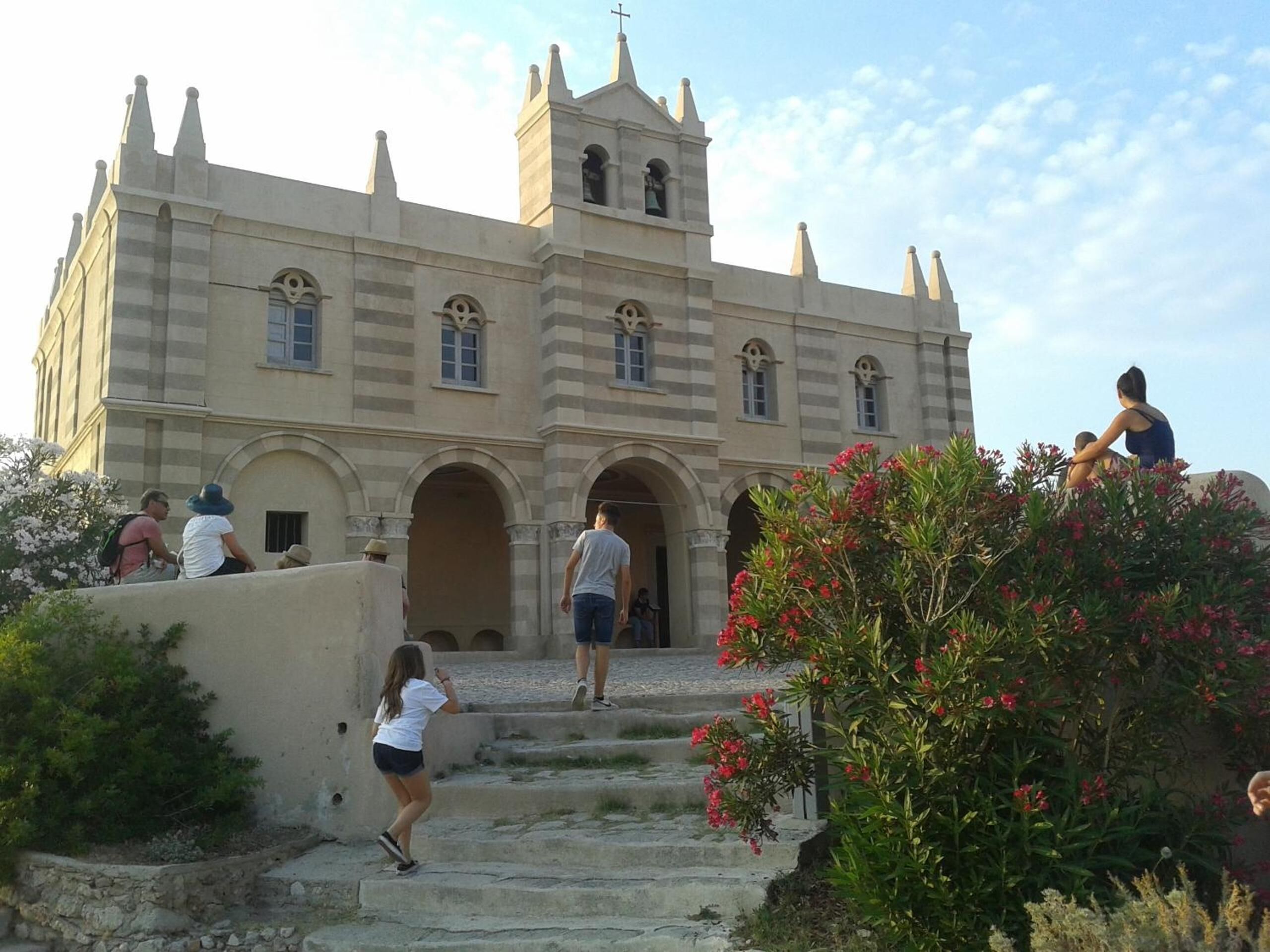 A historic building with a central tower, arched doorways, and a staircase leading to the entrance.