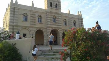 A historic building with a central tower, arched doorways, and a staircase leading to the entrance.