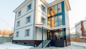 A modern multi-story building with a glass facade, a covered entrance, and a staircase leading to the entrance. - Keremet Hotel (Almaty)