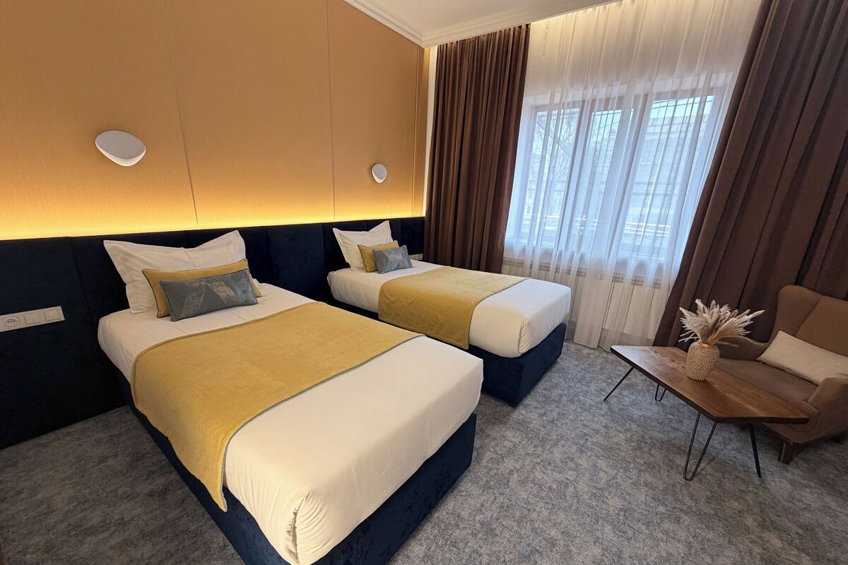A hotel room with two beds, a small table, and a sofa.