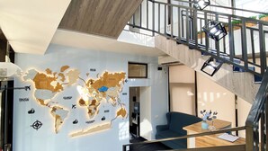 A modern interior with a world map mural, a staircase, and a seating area. - Keremet Hotel (Almaty)