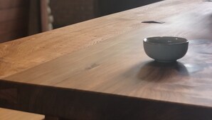 A wooden table with a bowl on it, a bench, and a door with windows in the background. - Village B&B (Lugu)