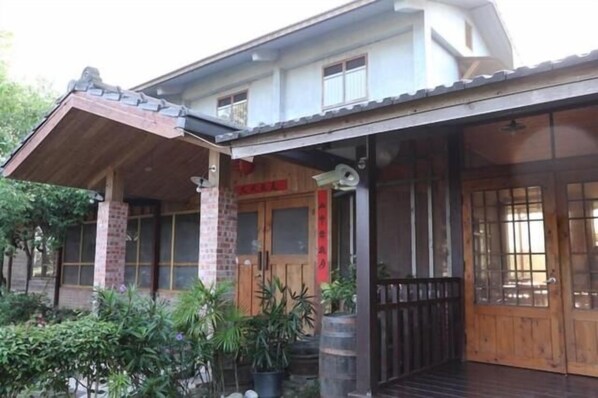 A traditional building with a wooden porch, large windows, and a brick facade. - Village B&B (Lugu)