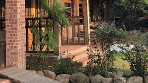 A wooden building with a brick chimney, large windows, and a covered porch. - Village B&B (Lugu)