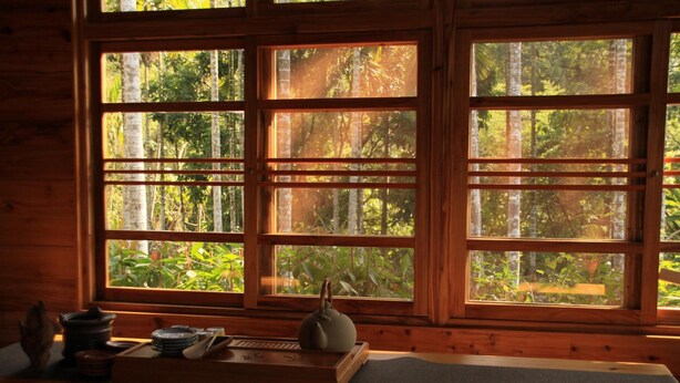 A room with large windows, a wooden table with a teapot, and a tray with tea utensils. - Village B&B (Lugu)