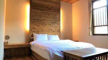 A wooden-paneled bedroom with a bed, bedside table, and a window with curtains.