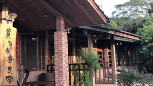 A traditional wooden building with a brick column, wooden beams, and a covered porch. - Village B&B (Lugu)
