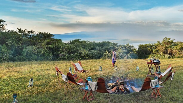 Un terrain de camping équipé d’un foyer, de chaises et de lanternes.