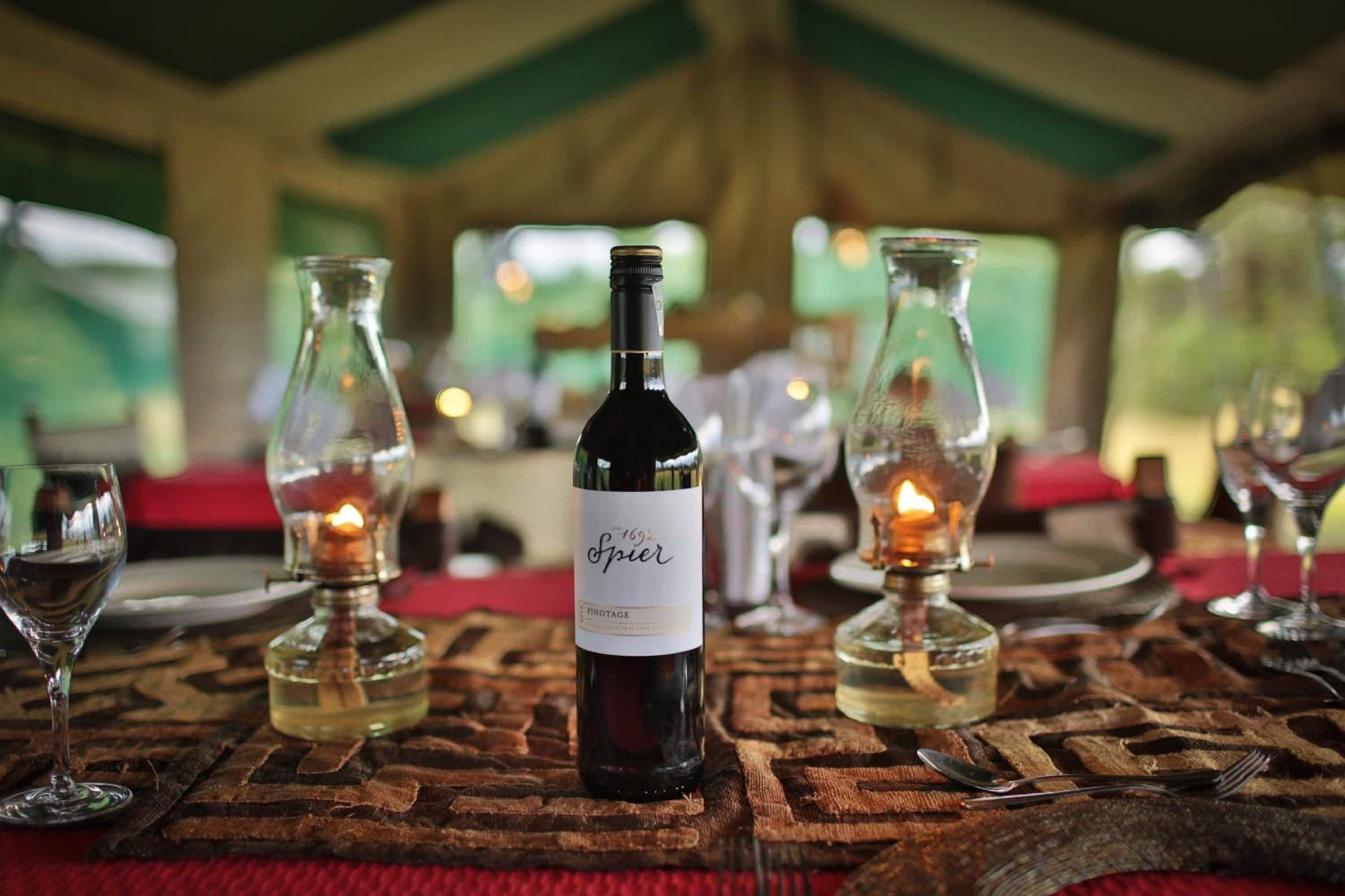 Une table dressée avec des verres à vin, une bouteille de vin et des chandeliers.