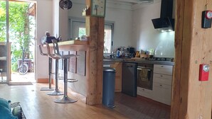 Una cocina amplia con vigas de madera, zona de comedor con taburetes de bar y vistas al exterior.
