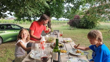 A family dining outdoors with a green car parked nearby.