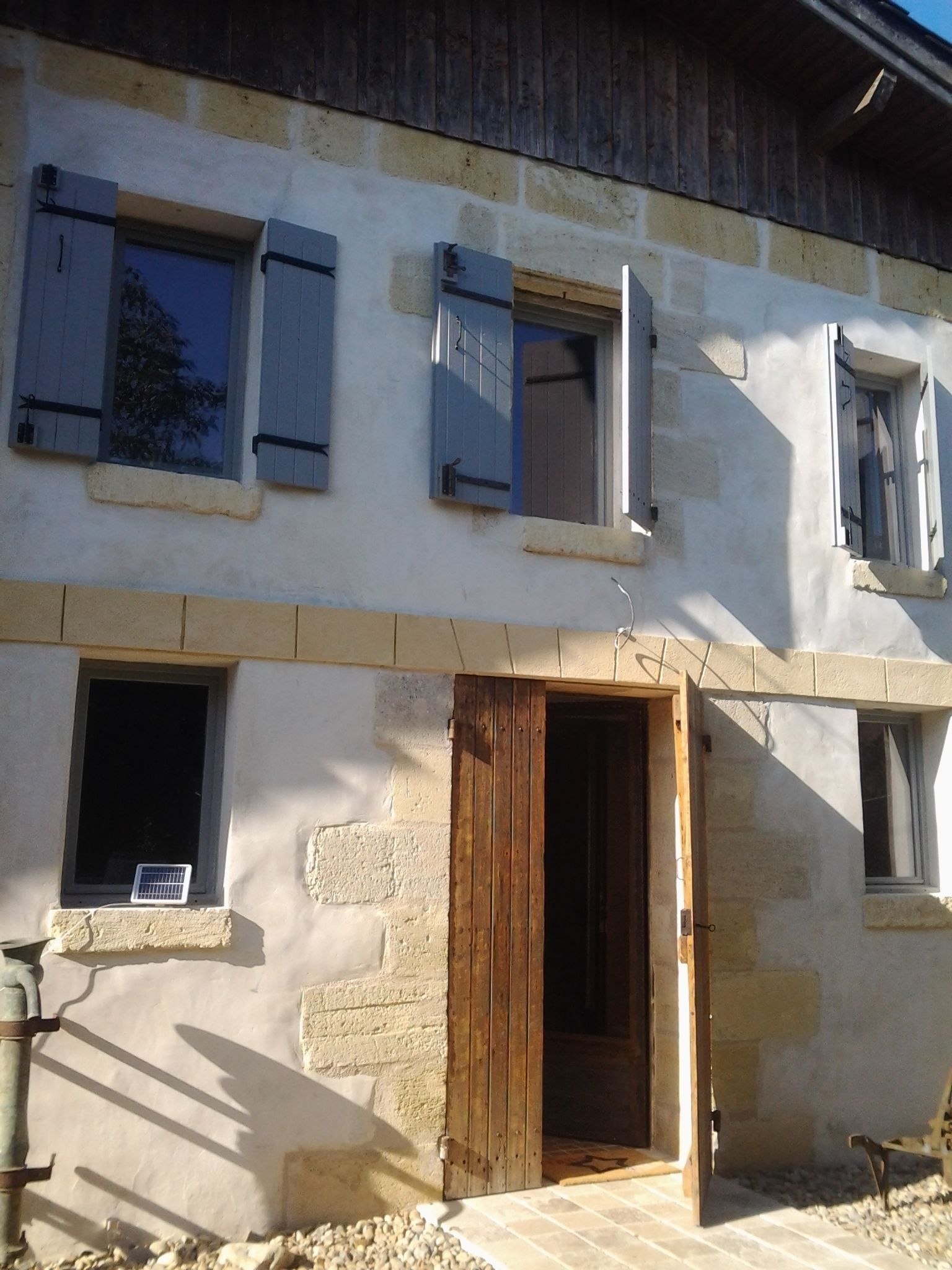 A two-story building with a wooden door and windows with shutters.
