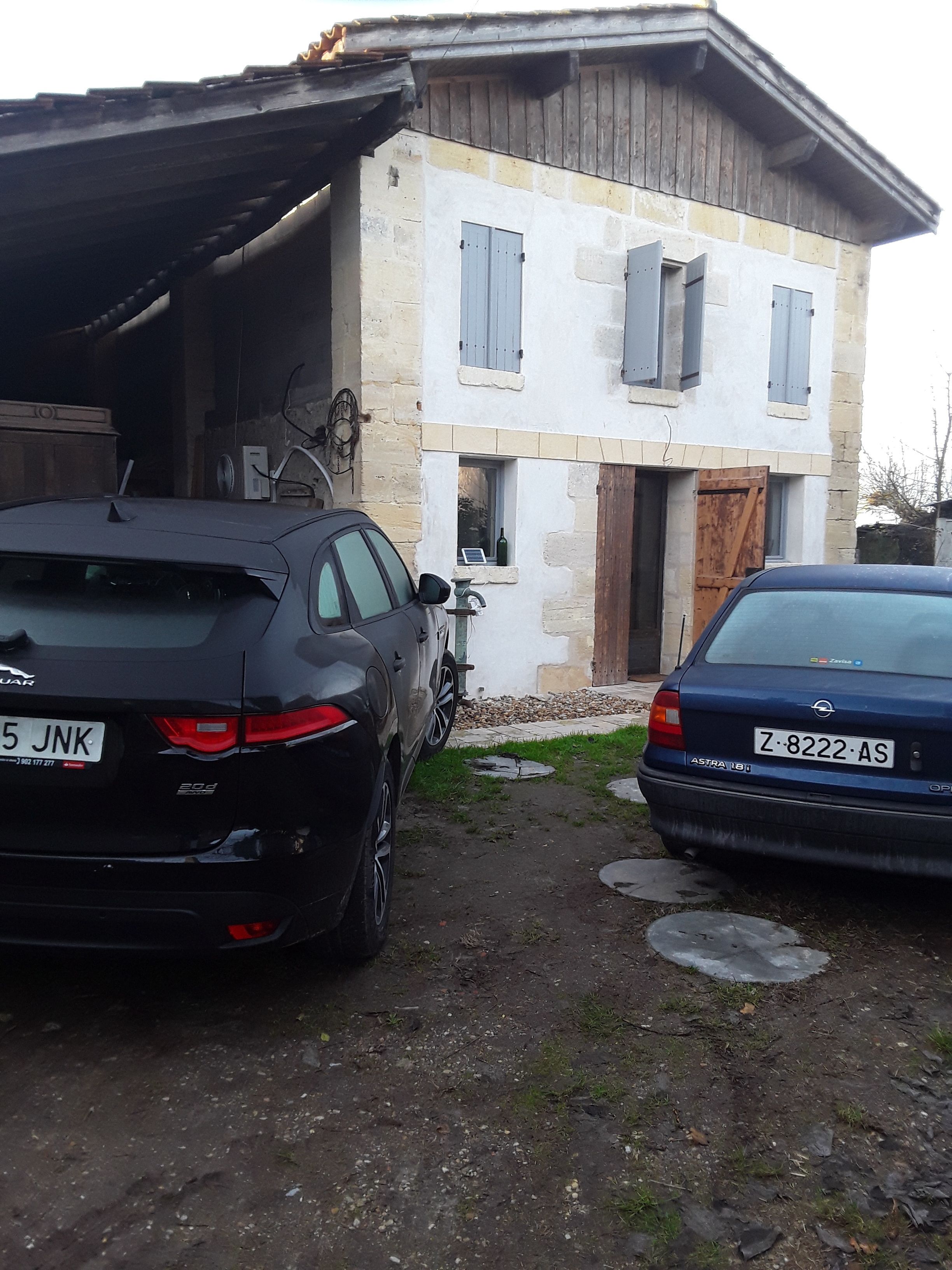 Two cars parked in front of a house with a stone facade and a wooden door.
