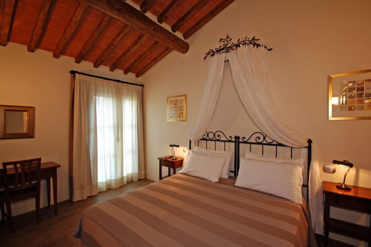 A bedroom with a bed, a desk, and a chair.