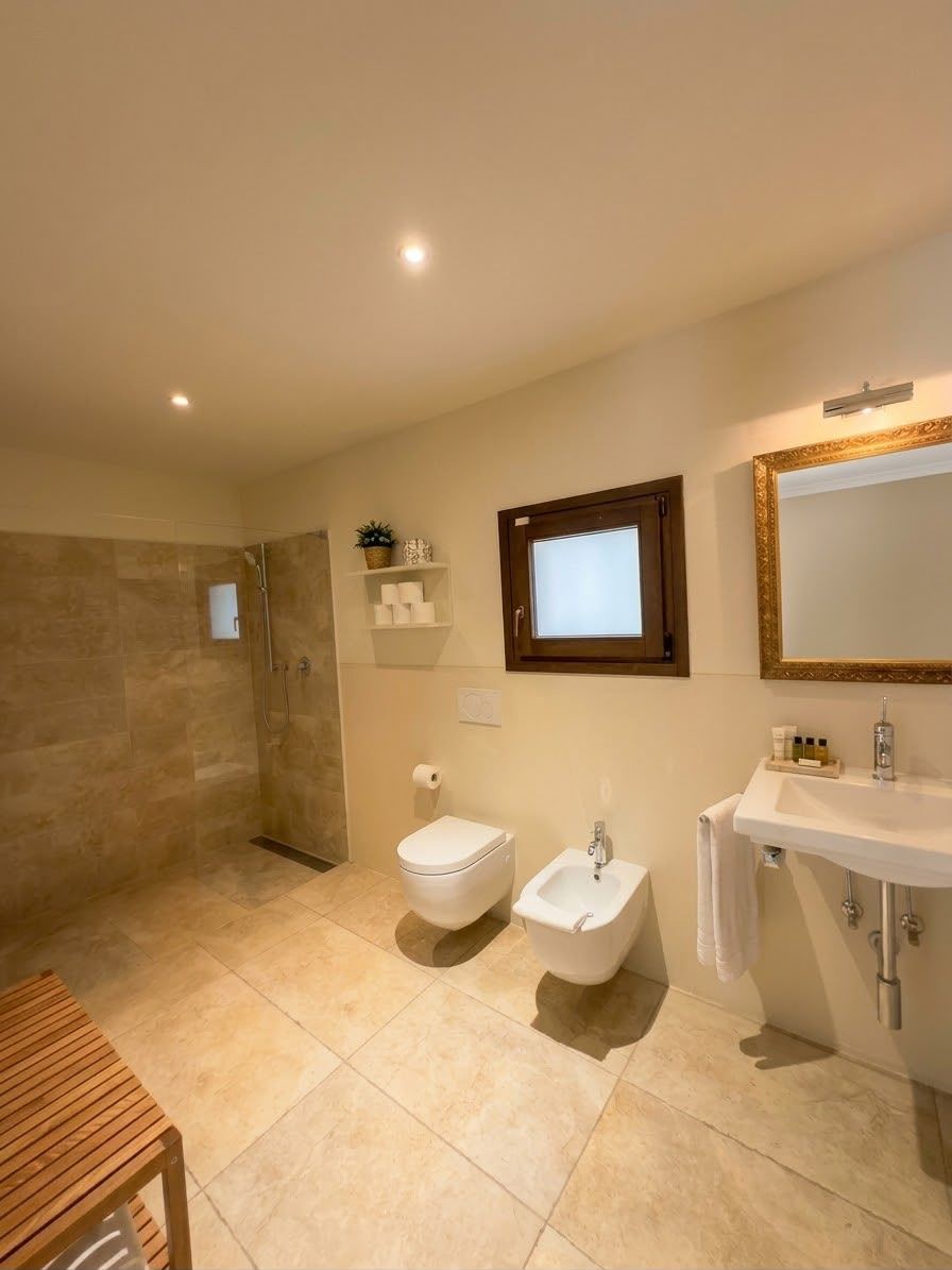 A bathroom with a shower, toilet, bidet, and sink.