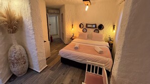 Une chambre confortable avec un lit, des tables de chevet, un luminaire fixé au mur et un grand vase.