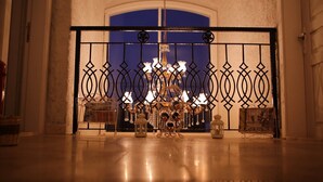 Un lustre doté de plusieurs ampoules et d’éléments décoratifs, dans une pièce au sol poli et agrémentée d’une grille en métal décorative.
