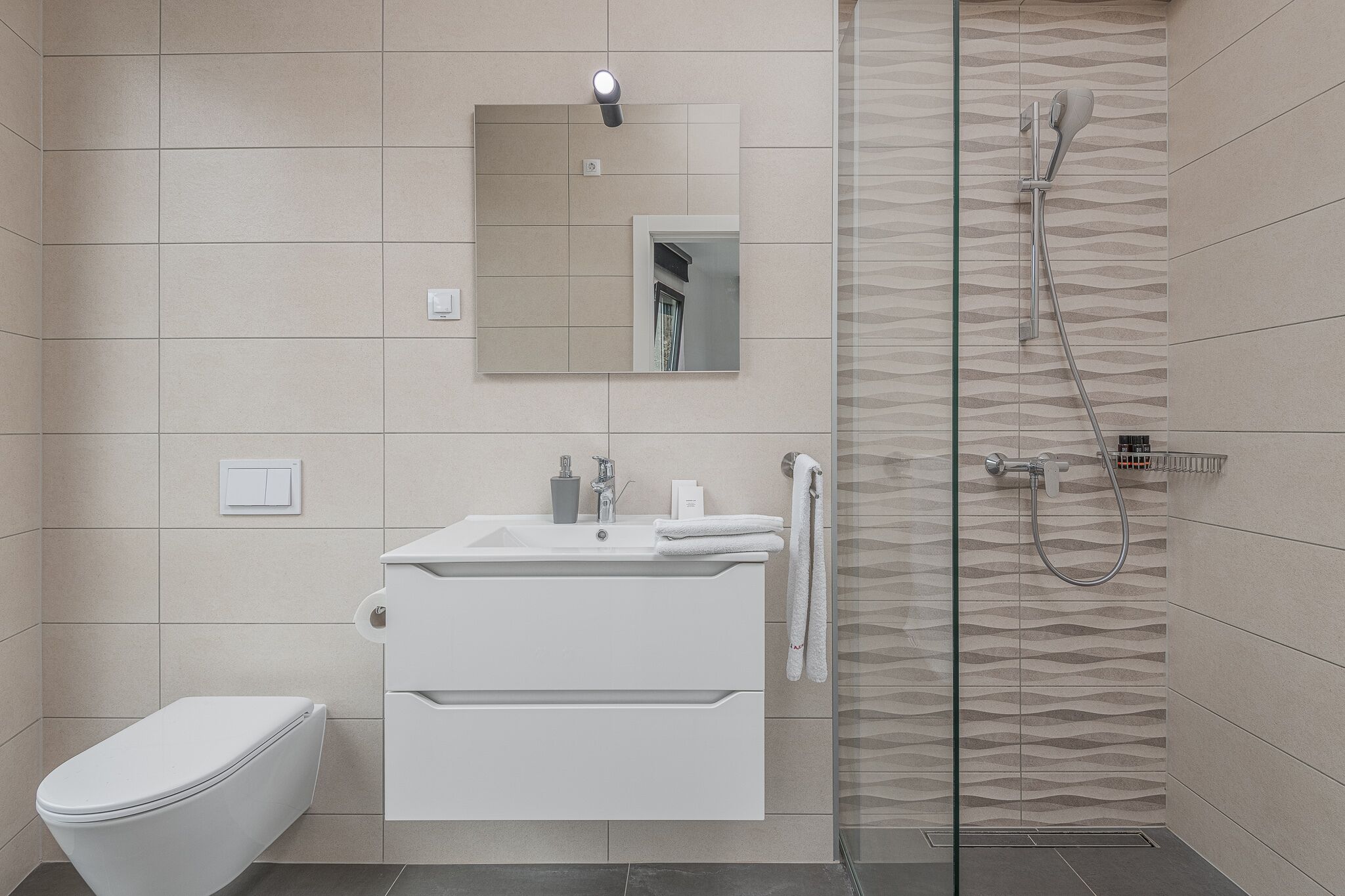 A modern bathroom with a toilet, sink, and shower.