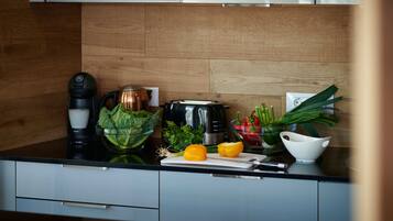 A kitchen with a coffee maker, a kettle, a toaster, and fresh vegetables on the counter.