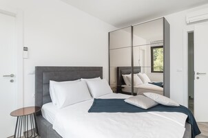 Ein modernes Schlafzimmer mit einem großen Bett, einem kleinen Tisch und einem Schminkspiegel.