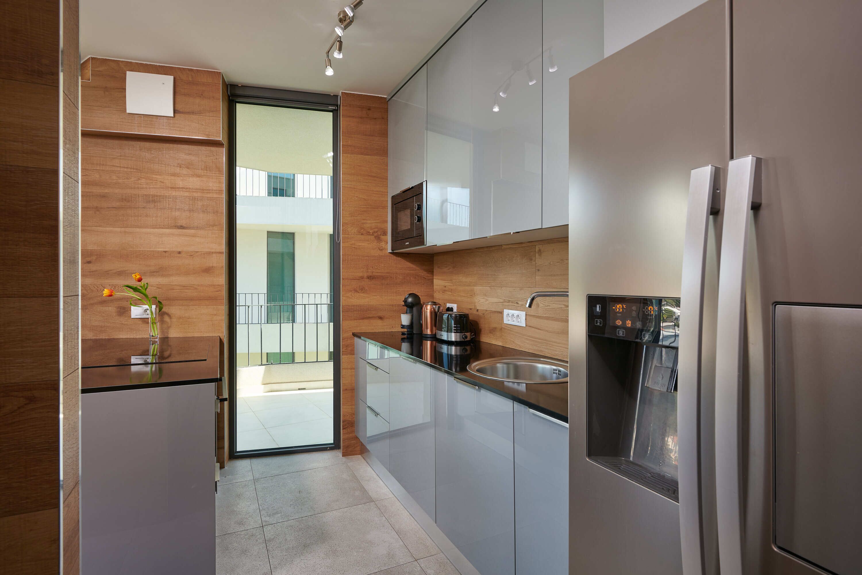 A modern kitchen with a built-in oven, microwave, and stainless steel refrigerator.