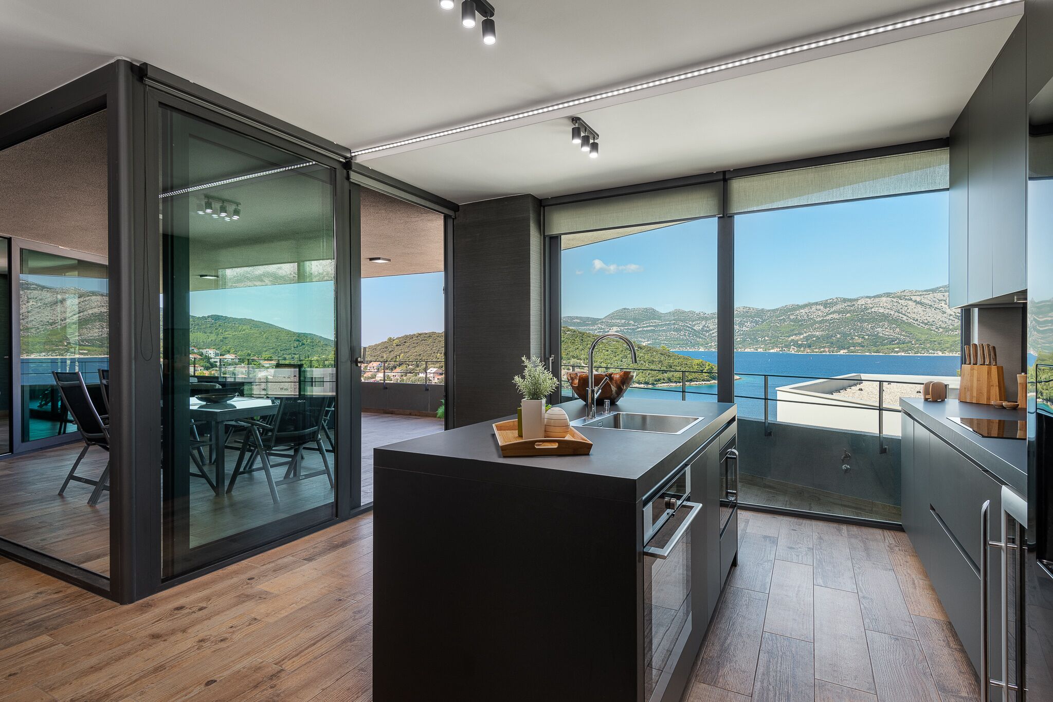 Et moderne køkken med en stor ø, et spiseområde med udsigt og en balkon med en smuk panoramaudsigt.