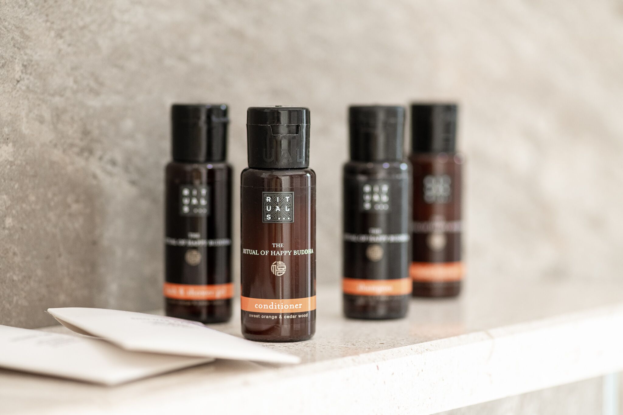Four bottles of RITUALS conditioner on a marble countertop.