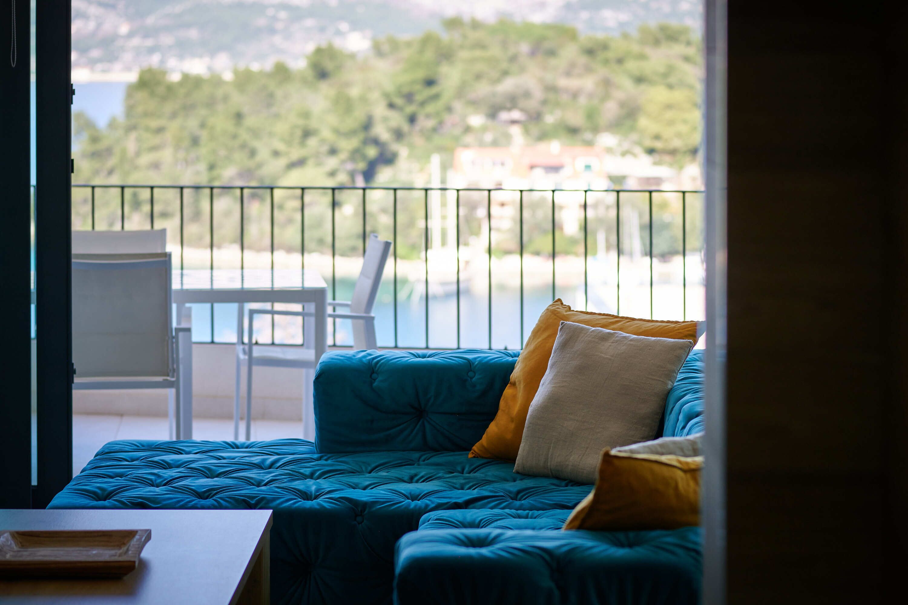 Ein Balkon mit einem blauen, gepolsterten Sofa, einem weißen Sessel und einem kleinen Tisch.