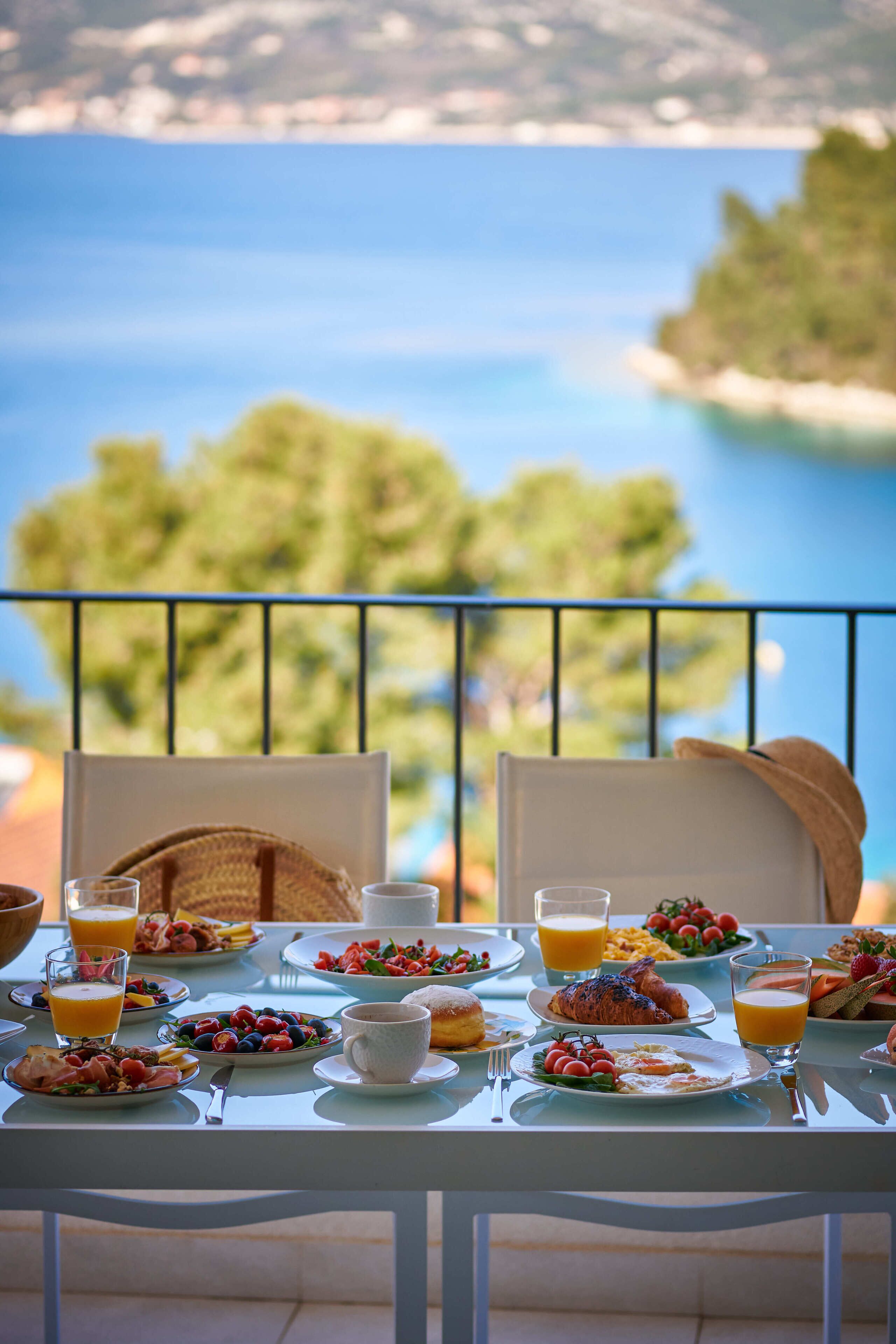 A table set with breakfast items and a view of the sea.