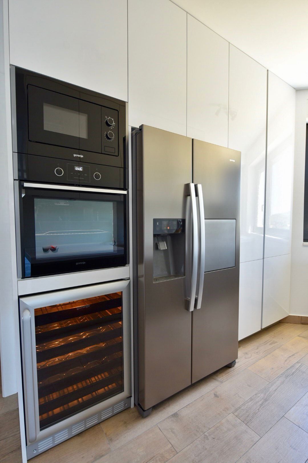 A kitchen with a built-in oven, a stainless steel refrigerator, and a microwave.