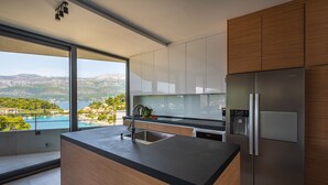 Una cocina moderna con una isla grande, electrodomésticos de acero inoxidable y vistas a un lago y montañas.