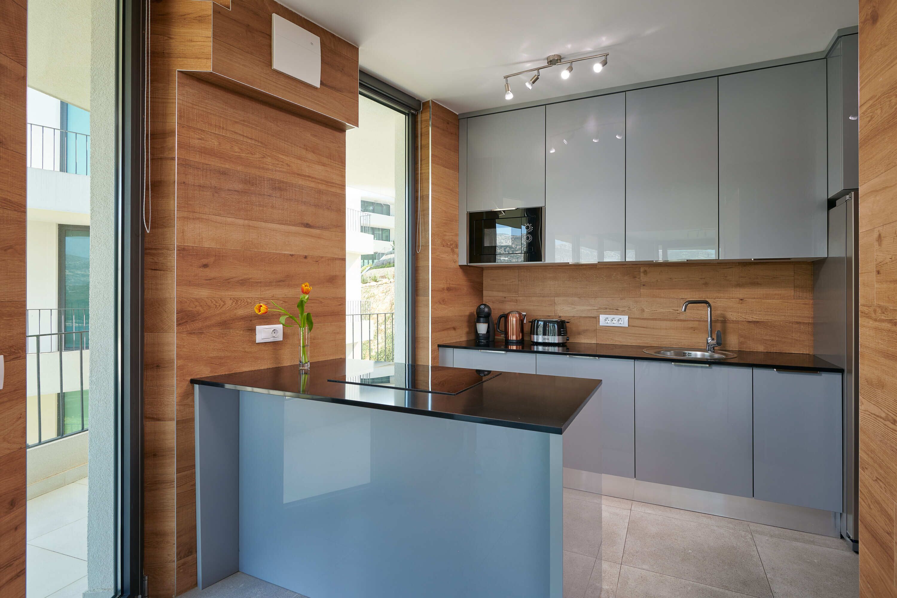 A modern kitchen with a glass island, stainless steel appliances, and wooden accents.
