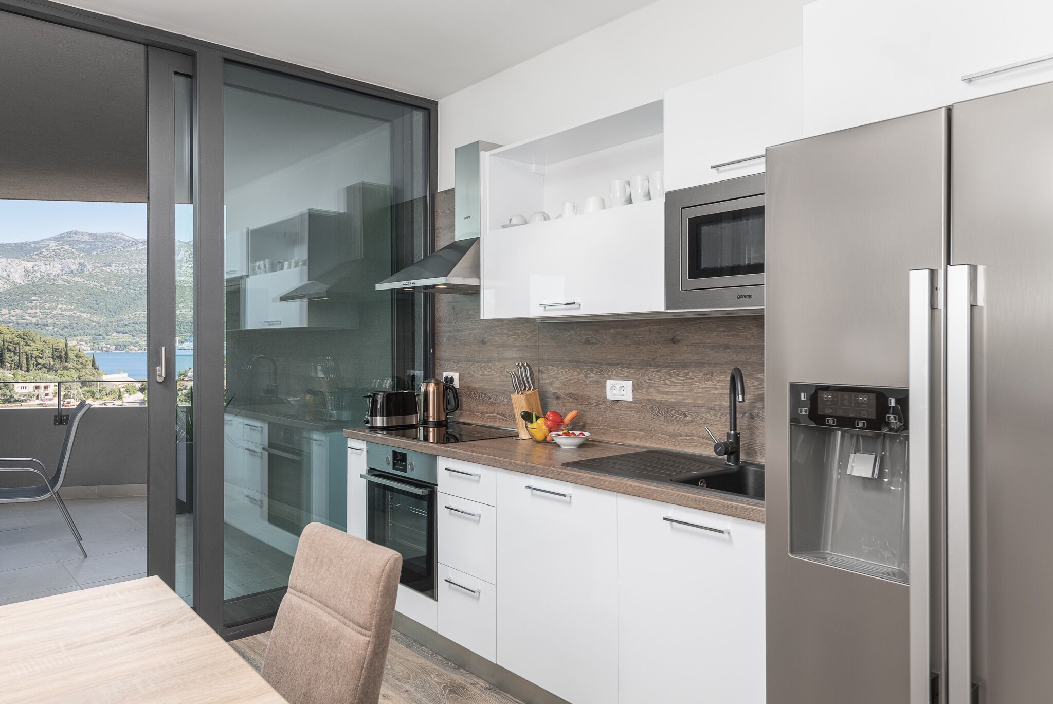 Una cocina moderna con microondas integrado, refrigerador de acero inoxidable y dispensador de agua.
