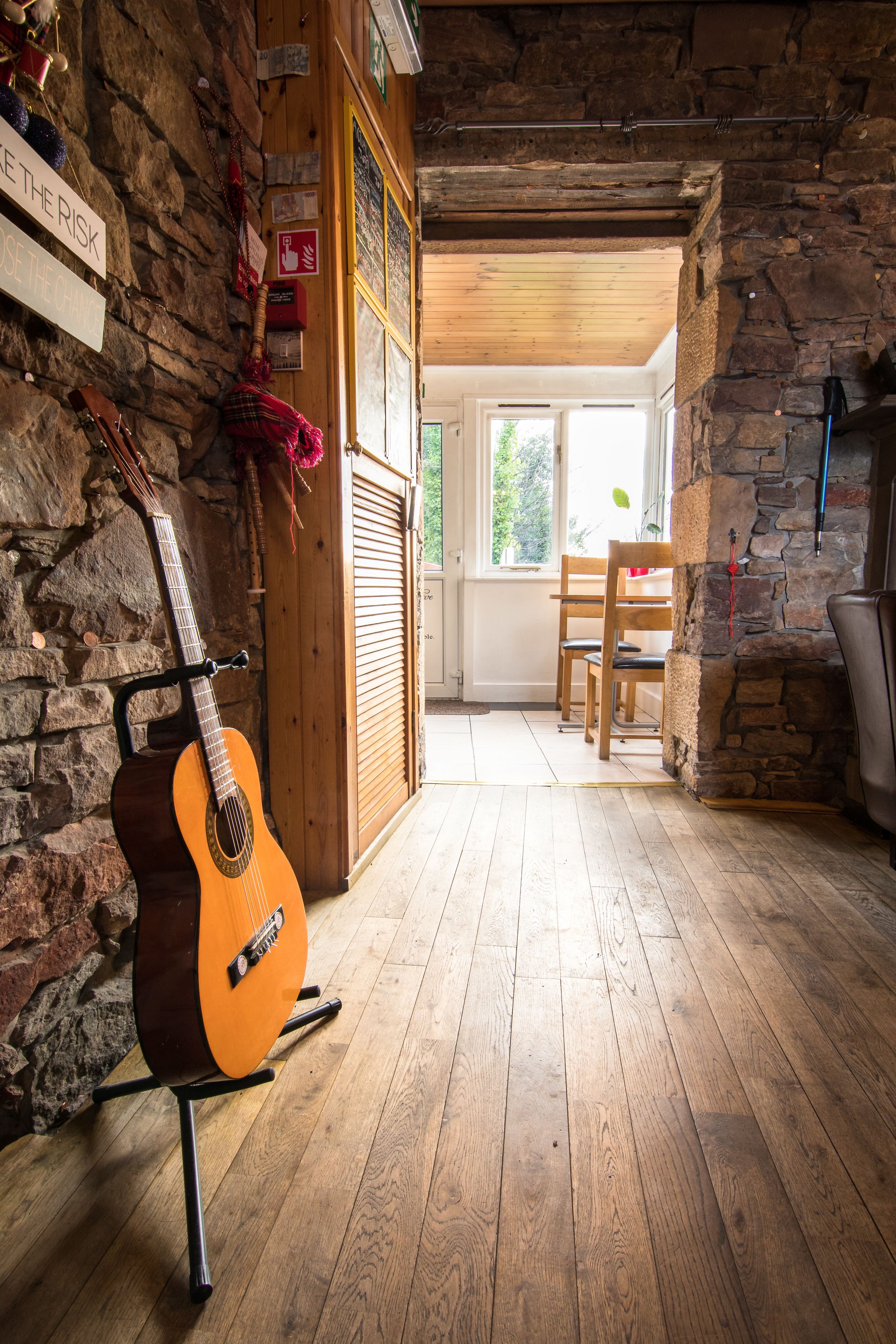 Ein rustikaler Raum mit Gitarre, Holzböden, Steinwänden und Kamin.