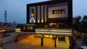 A modern hotel with a prominent sign, a covered outdoor area with plants, and a well-lit entrance. - Hotel Ivy (Raipur)