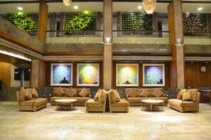 A lobby with multiple sofas and armchairs, a marble floor, and large stained glass windows. - Hotel Ivy (Raipur)