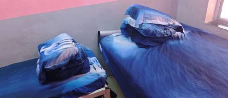 Two single beds with blue bedding in a room with pink and grey walls.