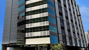 A tall, modern building with a prominent glass facade and a series of balconies.