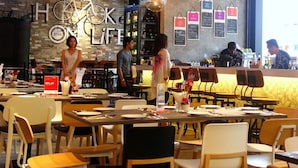 A restaurant with exposed brick walls, hanging pendant lights, and a bar area.