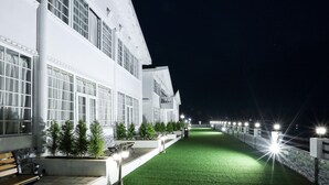 Un vialetto ben illuminato che conduce a un edificio con ampie finestre e un prato verde.