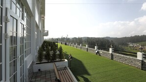 Un balcone con vista su un prato curato, un muro in pietra e un villaggio in lontananza.