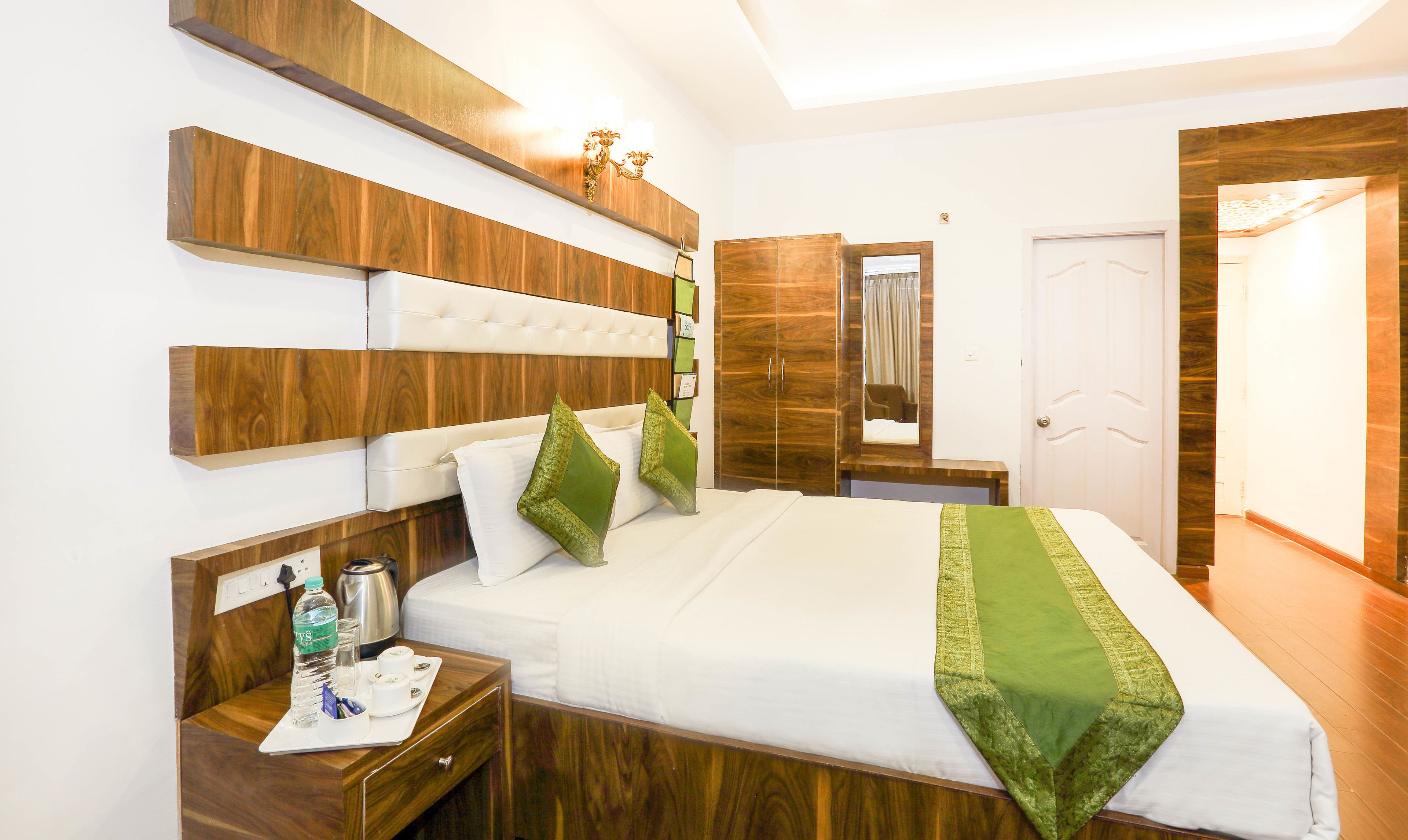 Ein ordentlich eingerichtetes Hotelzimmer mit einem großen Bett, einem Holzkopfteil, Nachttischen und einem Spiegel.