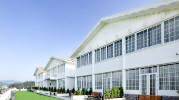 Edifício branco com janelas amplas e gramado verde.