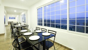 Un'area pranzo con tavoli e sedie, ampie finestre e vista sul paesaggio.