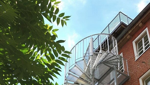 A multi-story building with a central spiral staircase leading to the upper floors. - Sleephotels (Hamburg)